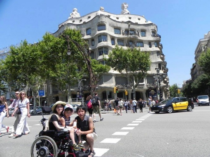 【写真】日差しがさしているバルセロナで車椅子に乗ってえいいちくんを抱いているゆりこさんとよういちさん。