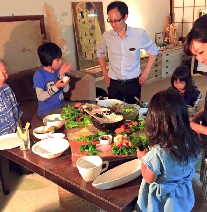 【写真】地域の子どもと大人が食卓に集まり楽しそうに食事をしている