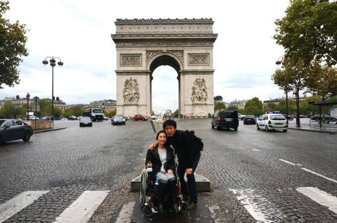 【写真】フランスの凱旋門の前でのゆりこさんとよういちさん。よういちさんがゆりこさんに寄り添っている