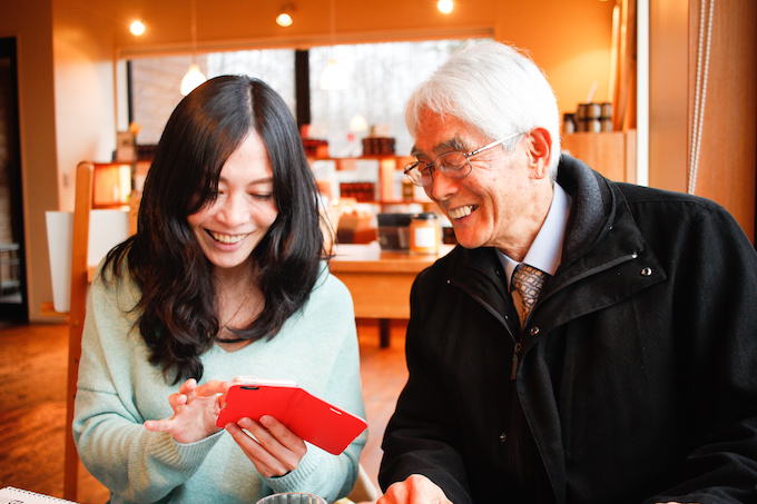 【写真】いぶきさんの人生を振り返るようにスマートフォンを見ている笑顔のいぶきさんとりゅういちさん。