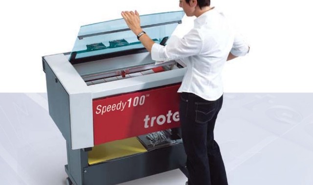 【写真】男性が大きなレーザー彫刻システムを操作している。とても大きく男性の腰ほどの高さがある。