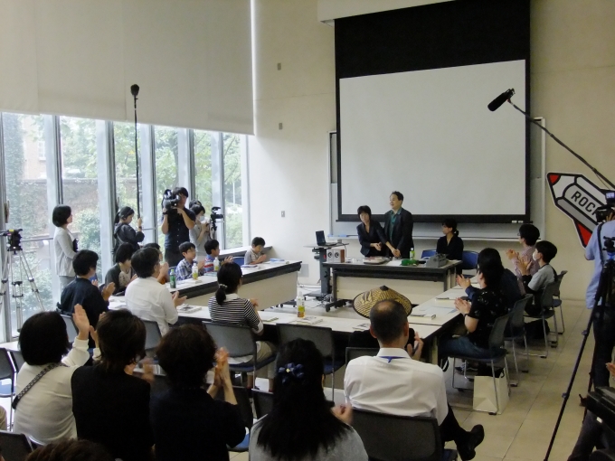 【写真】会議室での講義の様子。子どもと大人が入り混じって話を聞いている。