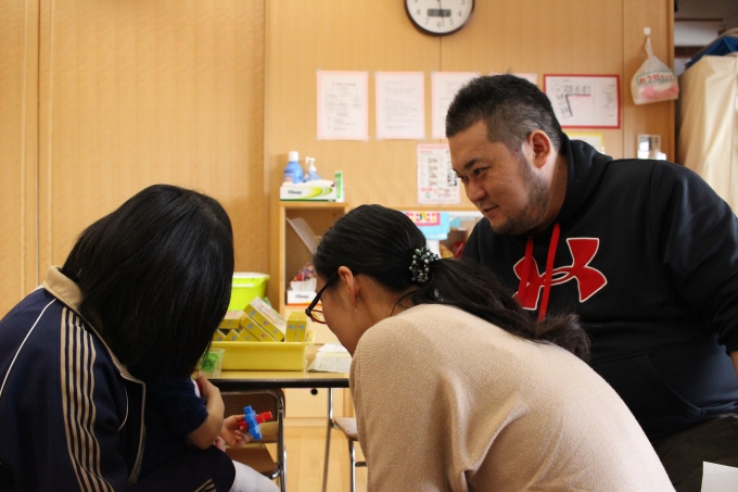 【写真】保育園の先生の微笑んでアドバイスをするおかだたいようさん