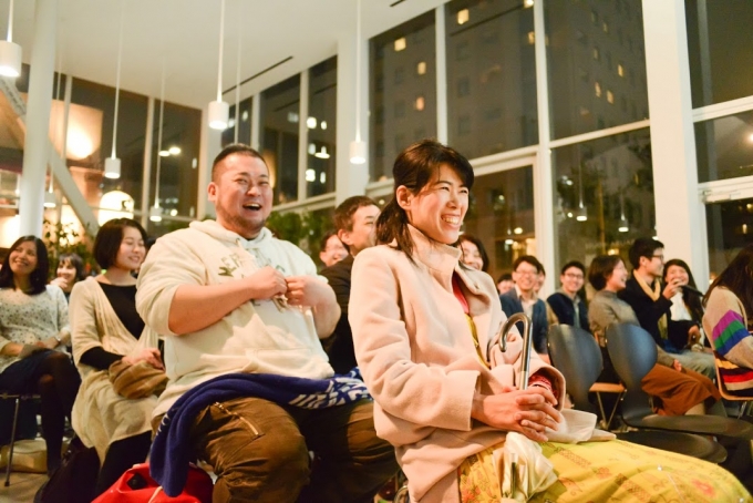【写真】満面の笑顔でゲストの話を聞く参加者たち。柔らかい照明に照らされた会場には、優しい空気が流れている。