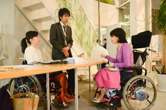 【写真】車椅子に乗る参加者の方と話をするおださんと旦那さんのよういちさん。