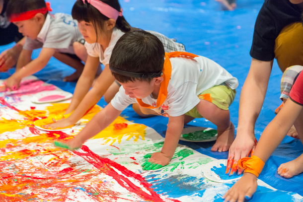 【写真】手に絵の具を塗って自由に絵を描く子どもたち。真剣な表情ながらもとても楽しそうな様子