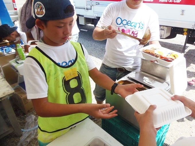 【写真】緊張した面持ちで、パックされた食品を渡す男の子