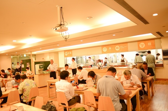 【写真】もりのキッチンの食堂。多くの人が椅子に座りお昼を頬張っている。