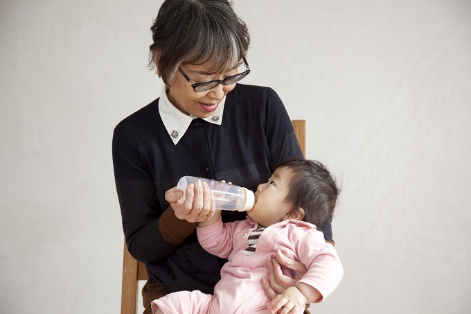 【写真】ばばらぼの商品の哺乳瓶で赤ちゃんにミルクをあげるメンバー