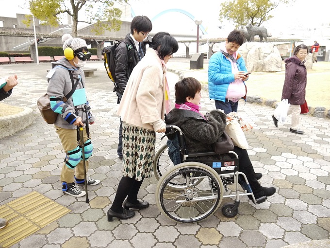 【写真】車椅子に乗ったりや高齢者体験をしながら街中で避難訓練を行う人たち