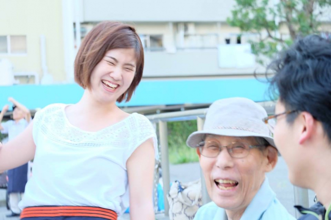 【写真】団地のおじいちゃんと一緒に笑っている学生スタッフ。2人とも楽しそうだ。