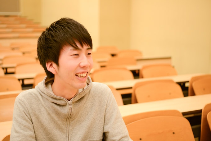 【写真】大学の講義室で笑顔で話すまつおかそうしさん