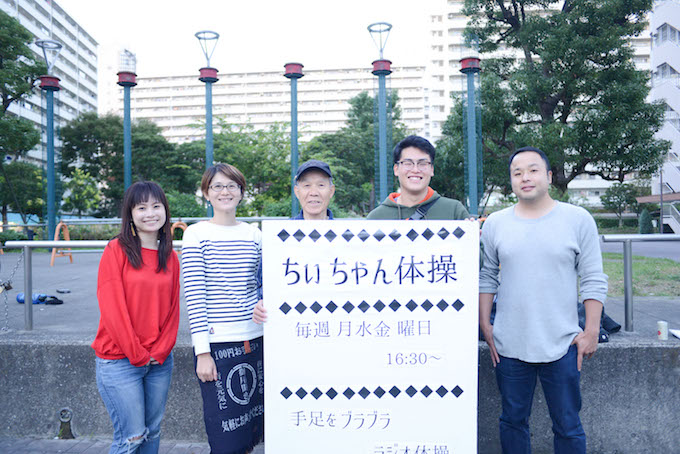 【写真】ちぃちゃん体操の看板の前で、笑みを浮かべ並んで立つごようききスタッフとsoar取材メンバー。それぞれ楽しそうだ。