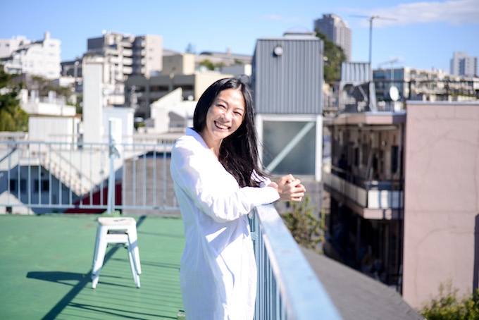 【写真】屋上で笑顔で立っているおざわいぶきさん。太陽の光がいぶきさんを明るく照らしている。