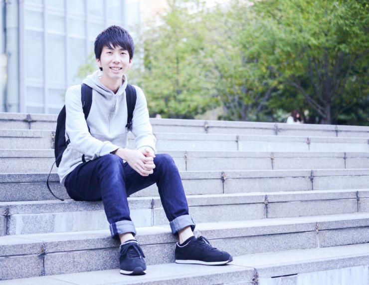 【写真】階段に笑顔で座っているまつおかそうしさん