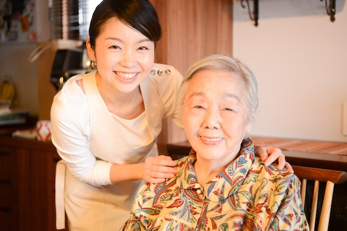 【写真】メイクが完了したおばあさまの肩に手を置き、笑顔でカメラを見つめるちしおさん