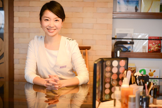 【写真】明るい表情でまっすぐカメラを見つめるちしおさん。横にはメイク道具が写っている