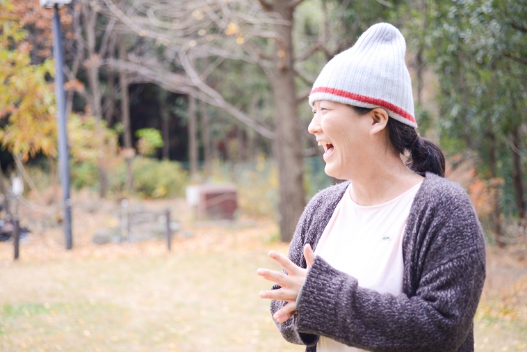 【写真】木々が並ぶ公園で大きく口を開けて笑うのむらちよさん