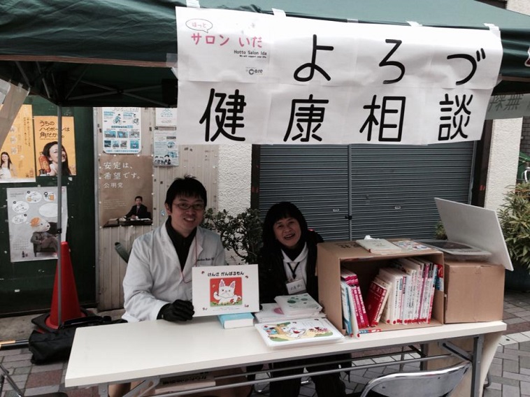 【写真】健康相談ブースにて、笑顔で人を待つ2人のスタッフ。