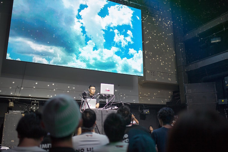 【写真】大勢の人が画面の前に立つDJに注目している。