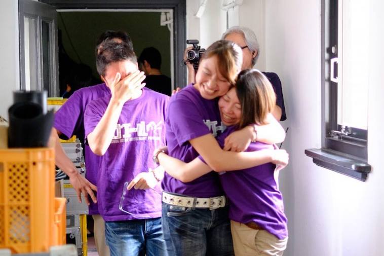 【写真】カナエールのTシャツを着たメンバーが、喜びを表現している。抱きしめ合う人や、感極まって目頭を抑える人。