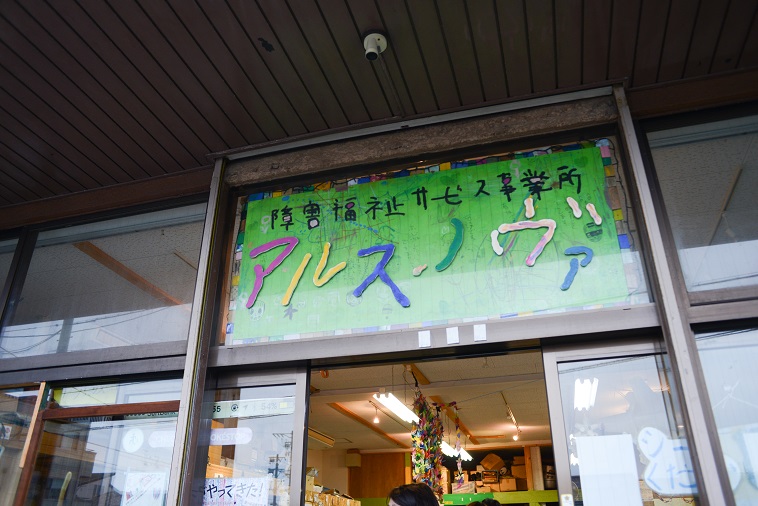 【写真】あるすのゔぁの入り口に看板が掲げてある。ピンクや黄色、青、緑、白、水色などで「あるすのゔぁ」と書かれている。