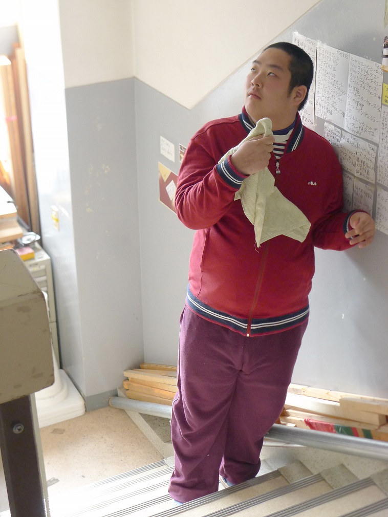 【写真】利用者のおおたりょうくん。階段の途中に立ち、なにやら上の方を眺めている。