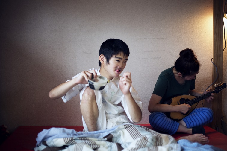 【写真】たけしくんがプラスチックの容器に石を入れて、音を聞いている。とても楽しそうだ。