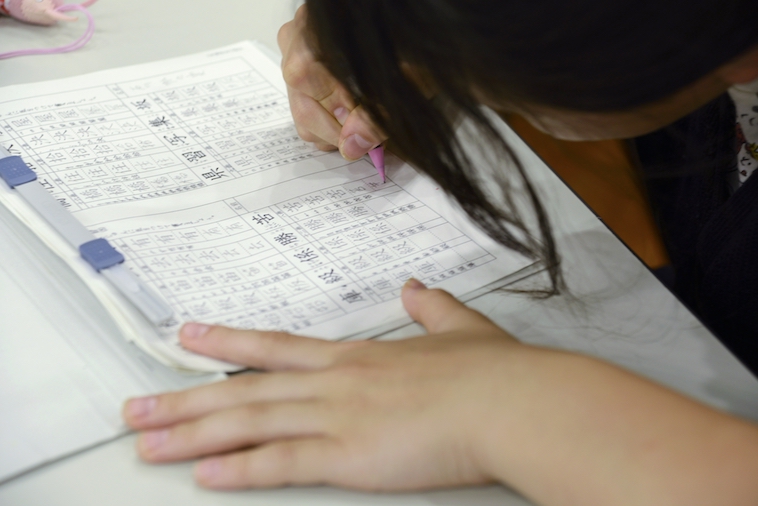 【写真】机に向かい、集中して漢字の練習を行う女の子。