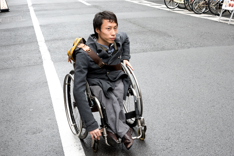 【写真】街道で車椅子に乗って移動するかんばらけんたさん
