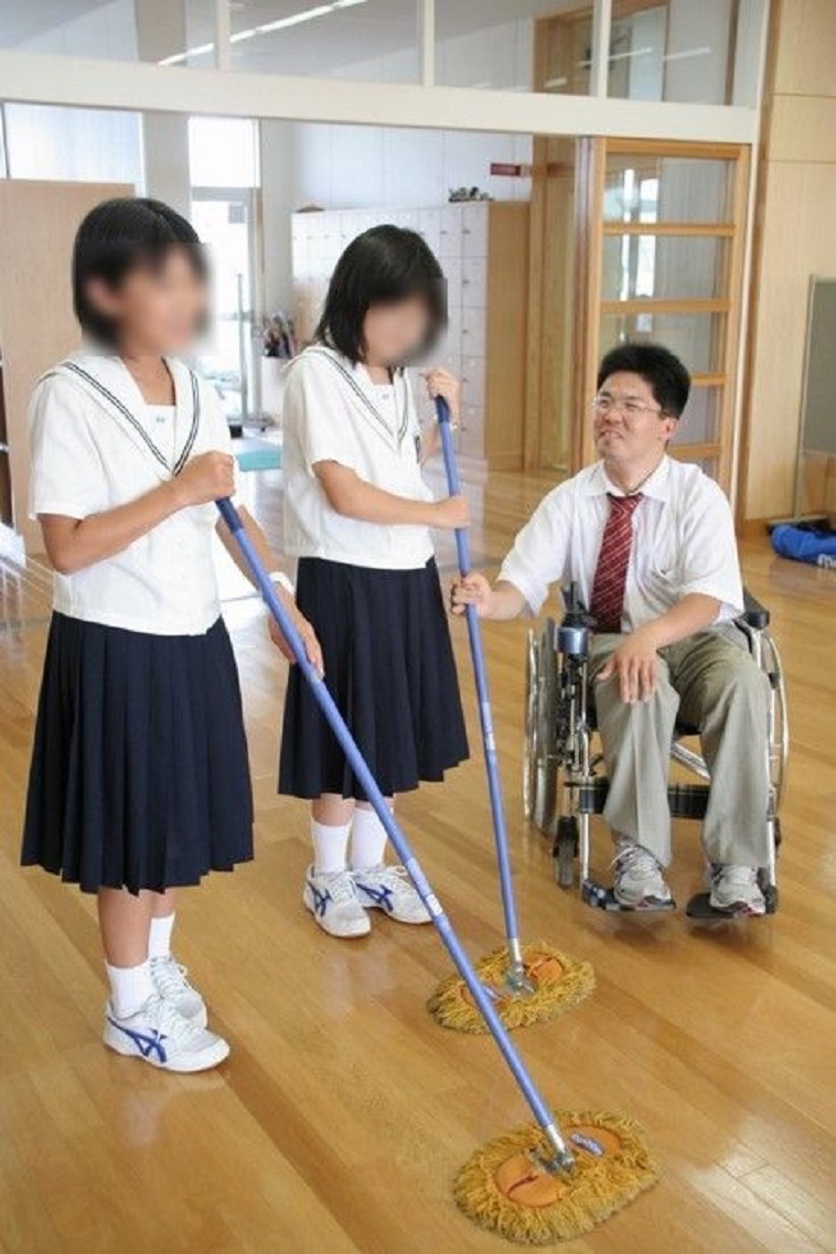 【写真】車椅子に乗った先生と掃除中の生徒が、話している。穏やかな空気が流れる。