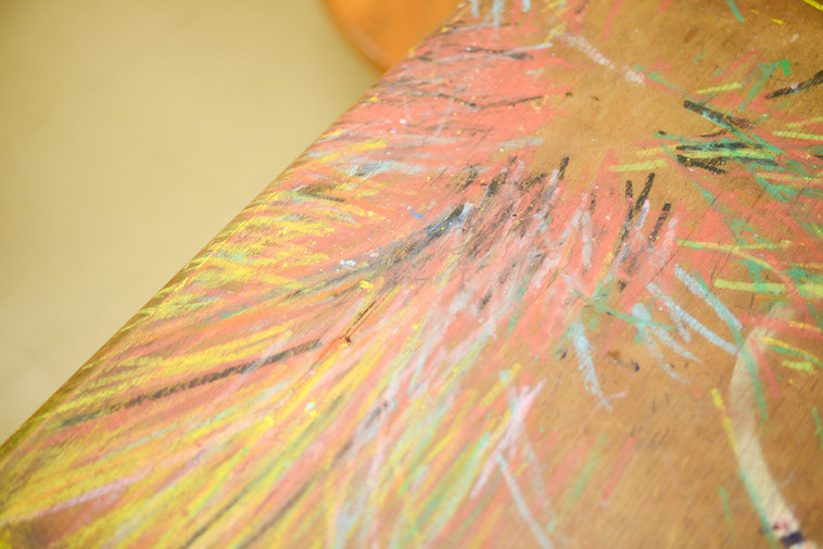 【写真】机にクレヨンでたくさんの線が描かれている。好きなことを思いのままにやった痕跡のようにも見える。