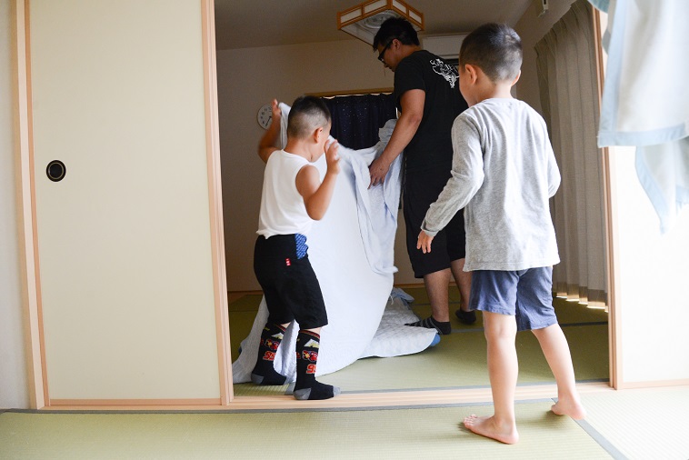 【写真】畳の部屋で布団をたたむたはらまさのりさんと子どもたち