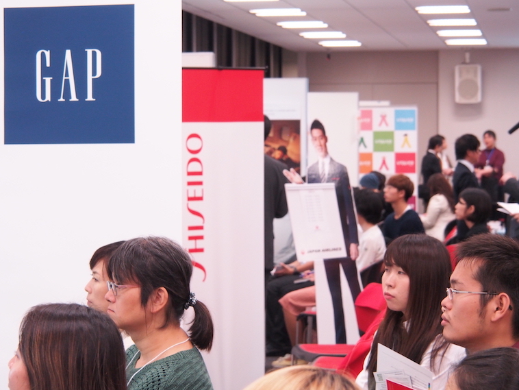 【写真】ブースでの企業の話に、真剣に耳を傾けるイベント参加者たち。