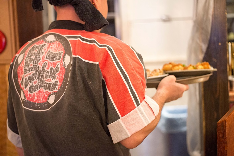 【写真】制服のハッピを着て餃子を運ぶCさん