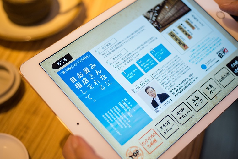 【写真】店内で注文に使うipadに「一般社団法人再チャレンジ支援機構」の概要が掲載されている