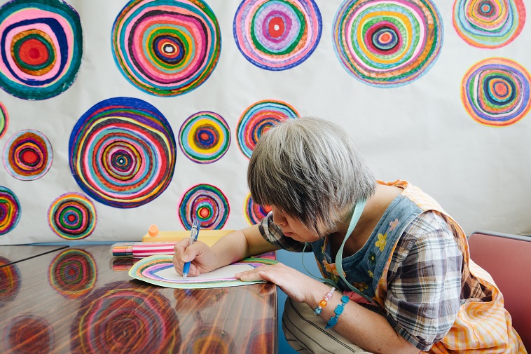 【写真】机に向かい、集中して絵を描く障害者アーティスト。