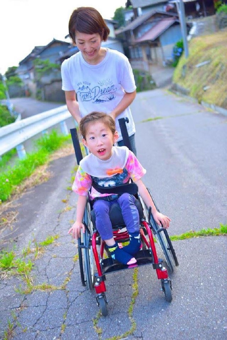 【写真】車椅子に乗るお子さんと、温かな眼差しで車椅子を押すかとうさん。