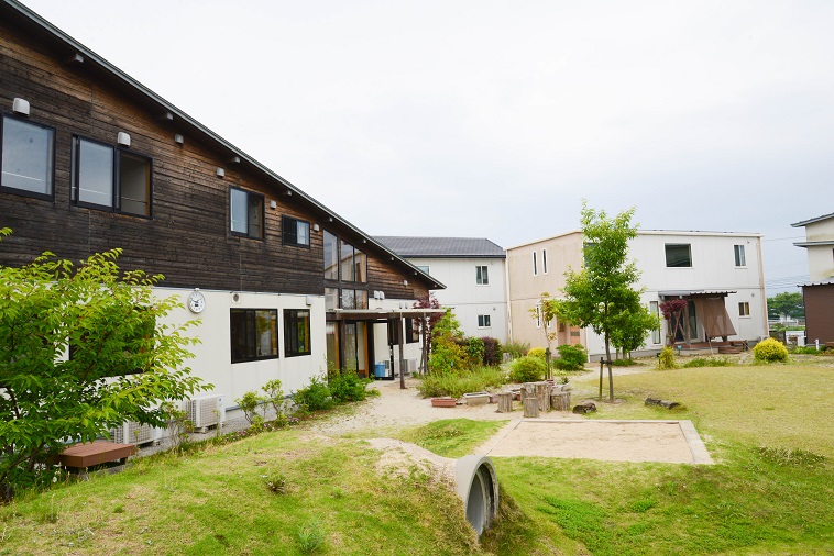【写真】緑の草や木々がある庭の周囲に住宅がある「子どもの村福岡」