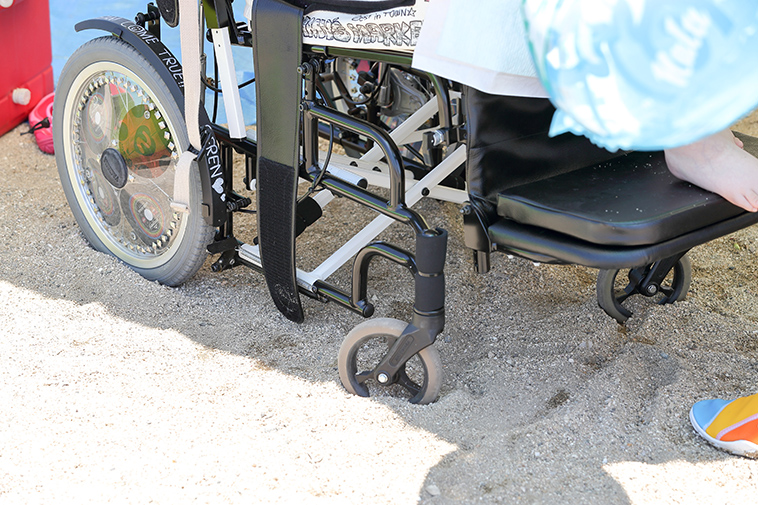 【写真】車椅子のタイヤが砂浜にめり込んでしまっている
