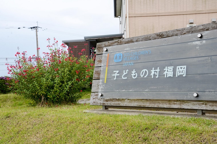 【写真】「子どもの村福岡」の看板。横には植物が生えている
