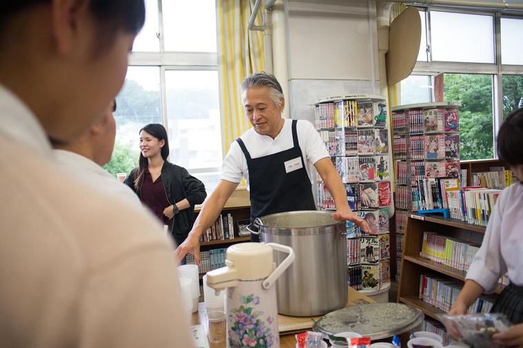 【写真】ボランティアさんが生徒にスープをついで渡している