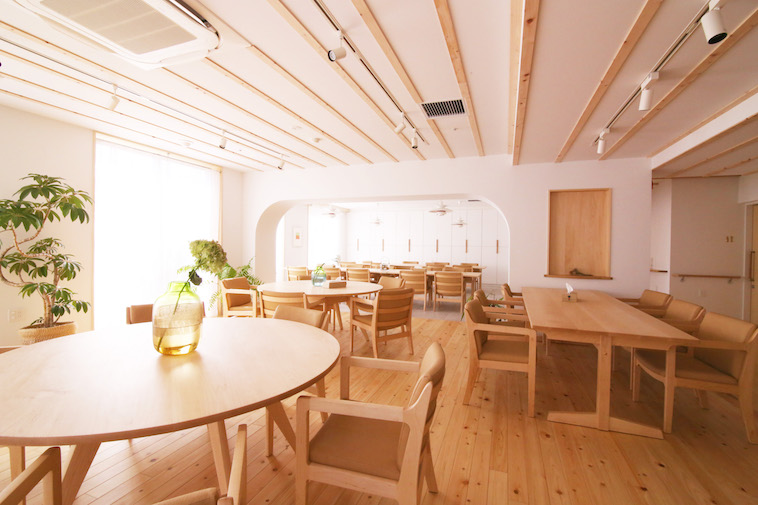 【写真】銀木犀の内部。木の床やテーブル、椅子が整然と並べられている。植物も飾られている