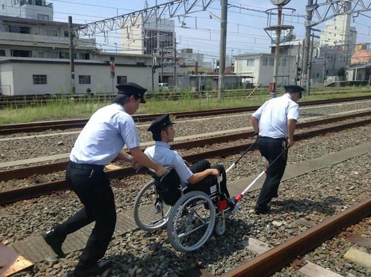 【写真】砂利の多い線路の上を、JINRIKIをつけた車椅子で移動訓練をする運転士たち