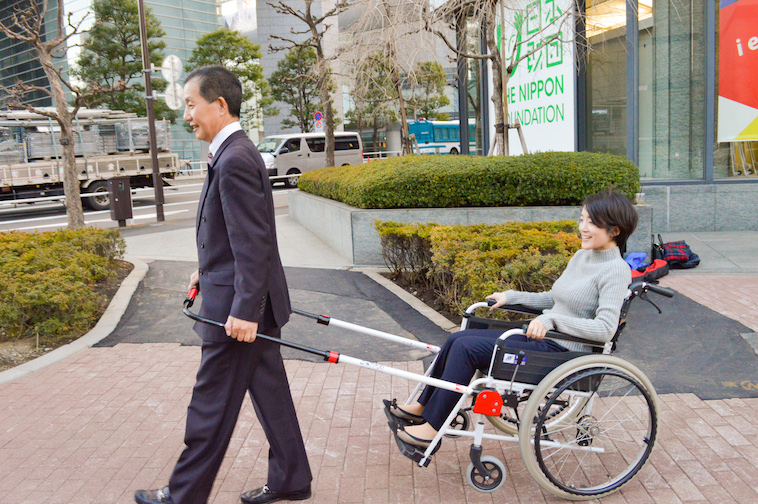【写真】インタビュー当日、JINRIKIを取り付けた車椅子に乗るインタビュアーと、JINRIKIを引っ張る社長のなかむらさん