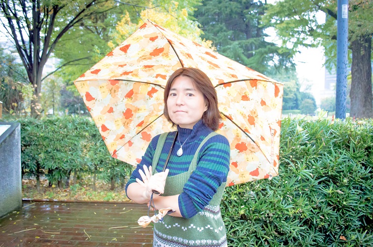 【写真】傘をさしてカメラに目線を向けるそでやまさん