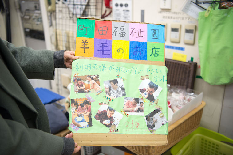 【写真】町田福祉園羊毛のお店の看板。手作りで、利用者さんの写真がたくさん貼られている