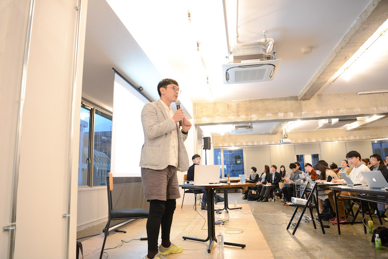 【写真】満員の会場で登壇しているかねまつさん