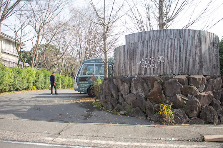 【写真】しょうぶ学園の入り口。木製の壁に素朴な形で「しょうぶ学園」書かれている。