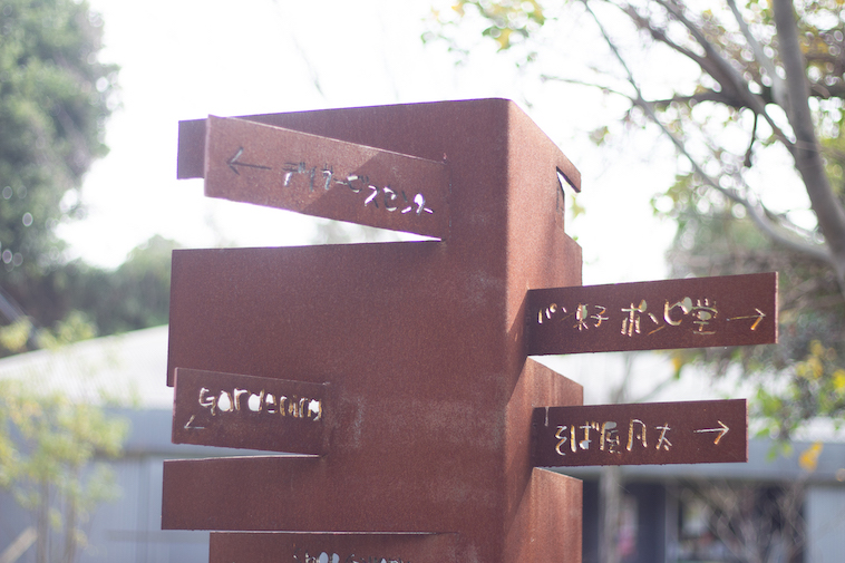 【写真】学園内にある標識。味のある文字でカフェや、パン屋、そば家などの方向を指し示している。